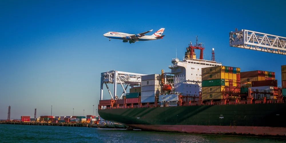 Container ship in port with a plane overhead